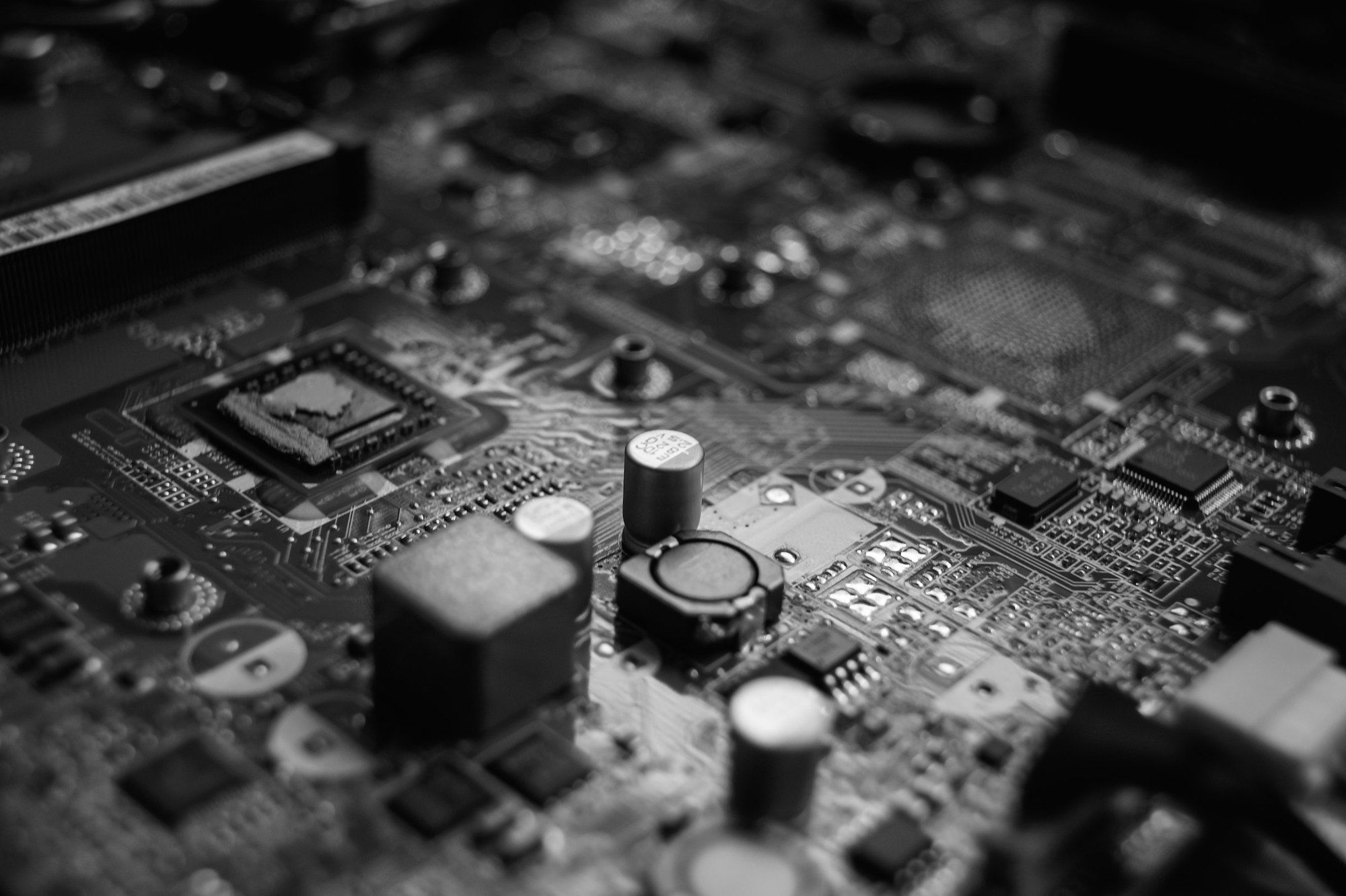 Motherboard in black and white, with capacitors and coils in the foreground